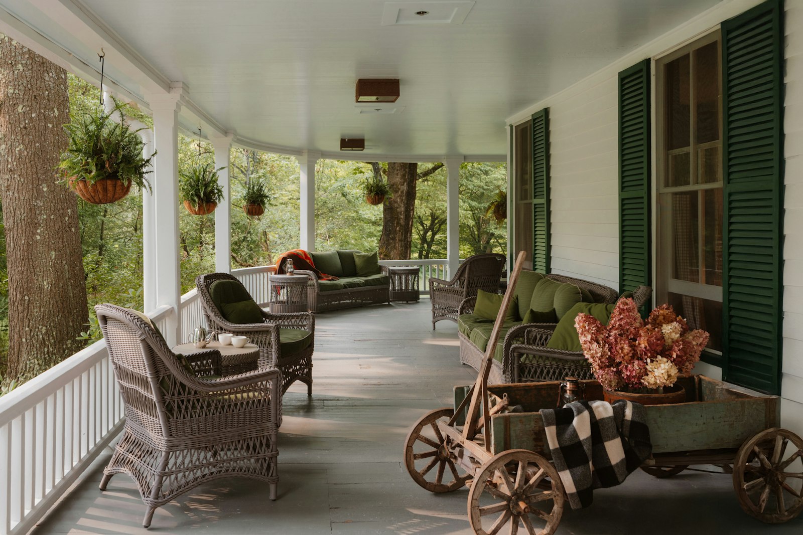 Sonoma porch at dusk — two glasses of wine, a wool blanket, soft golden light from inside